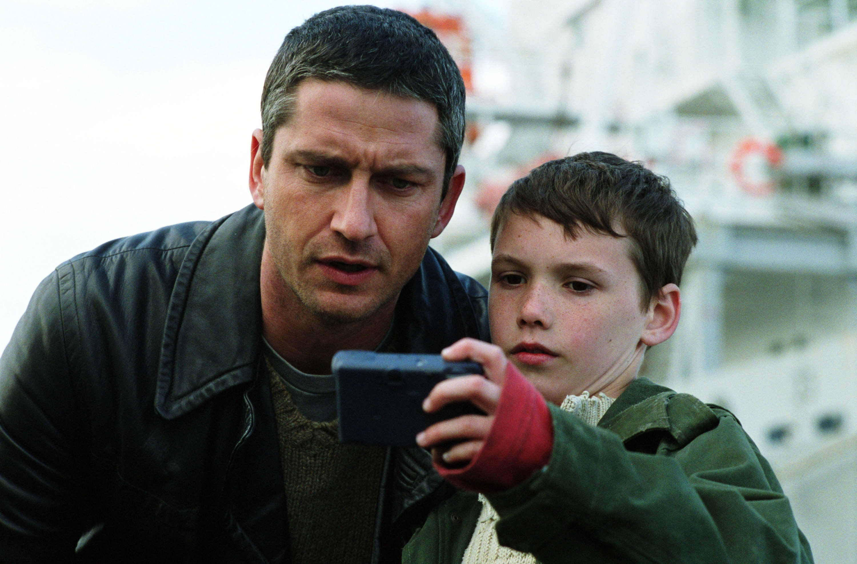 A man and a young boy stare intently in a digital camera