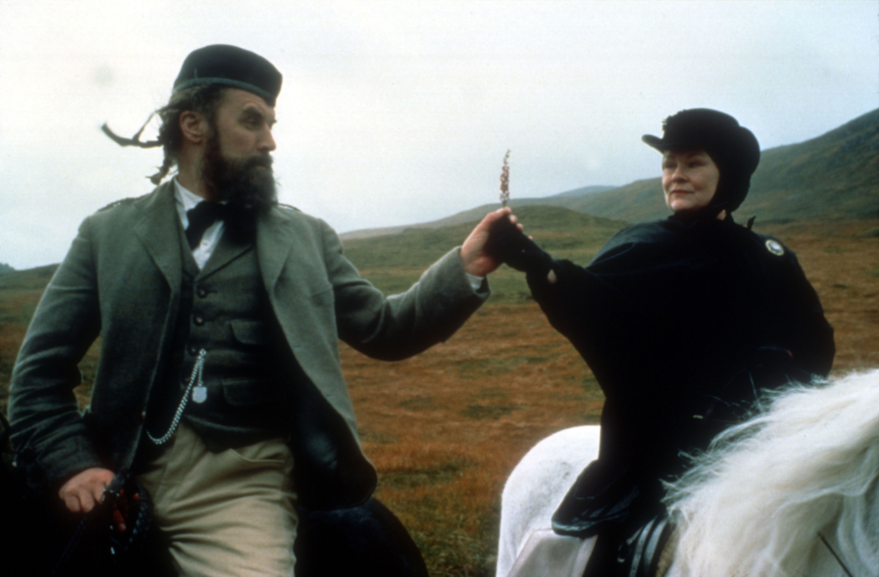 A woman in black on a white horse gives a feather to a bearded Scotsman