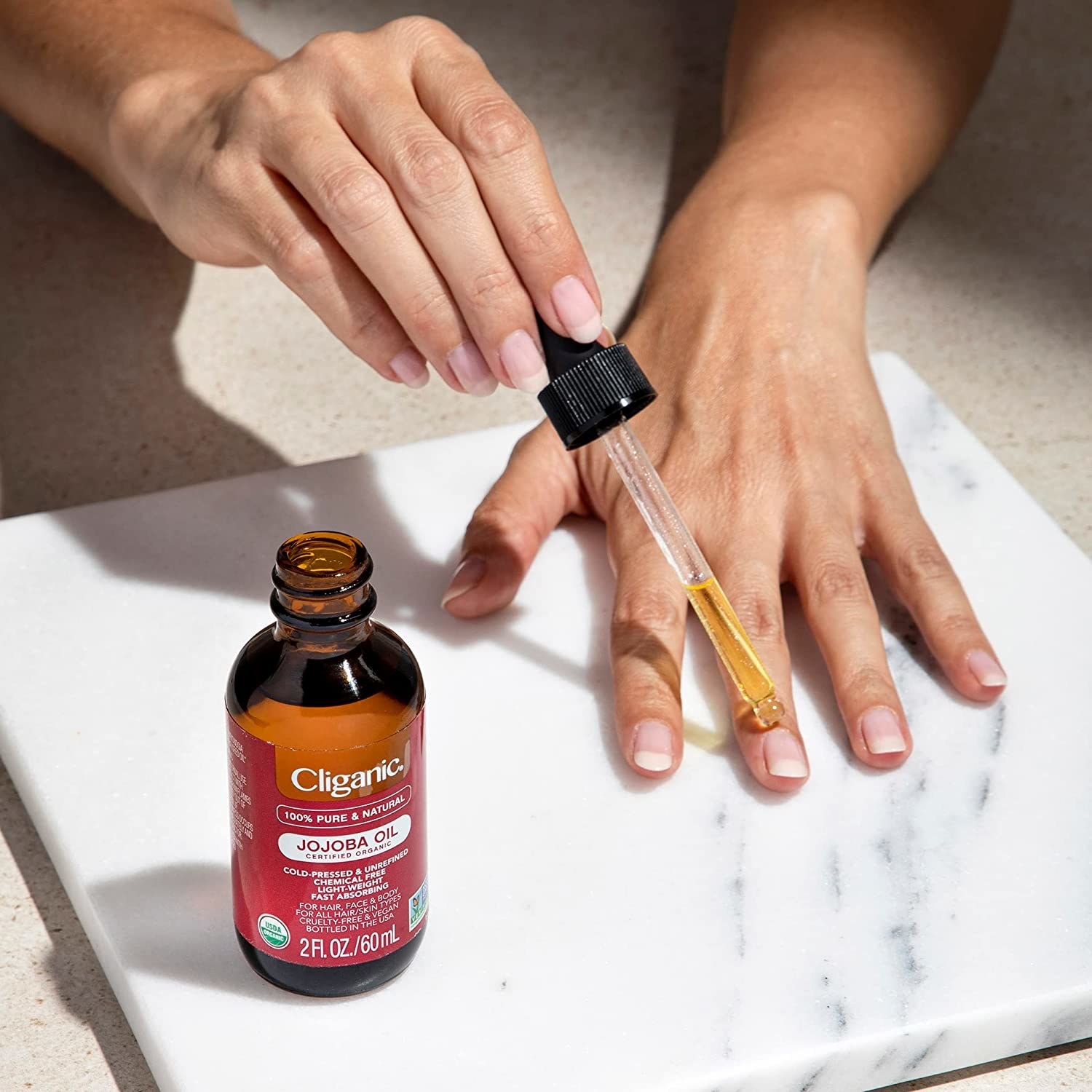 A person applying the jojoba oil to their nails
