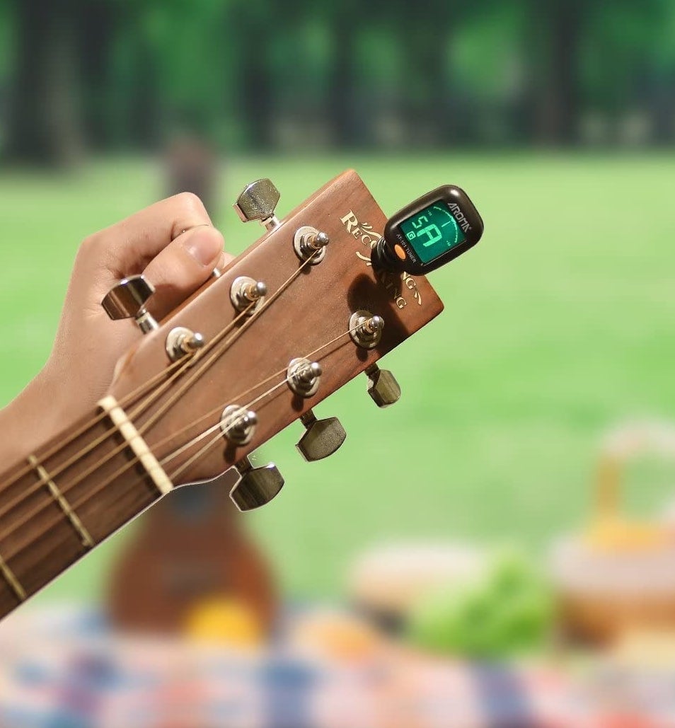A person using the tuner on their guitar