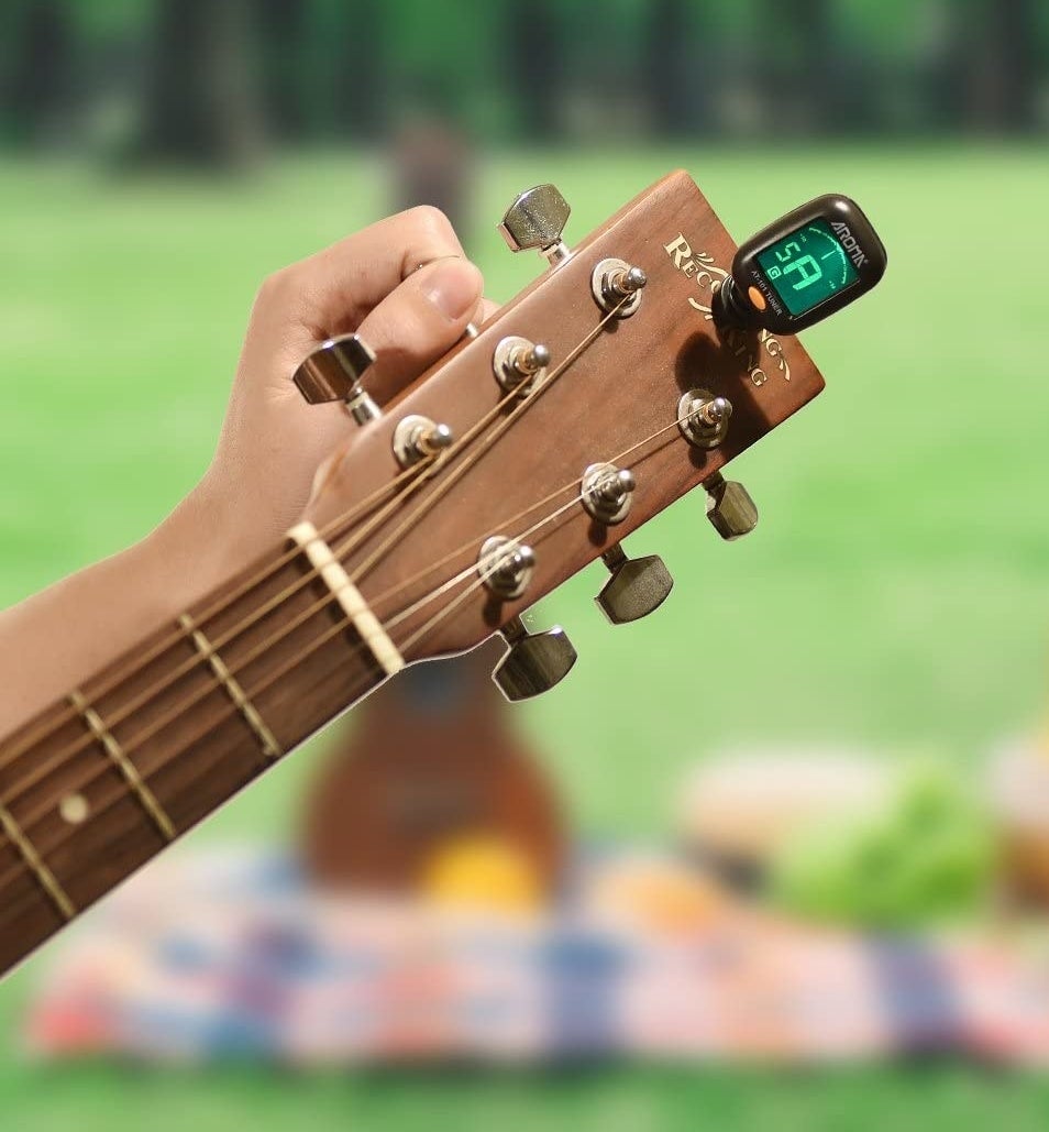 A person using the tuner on their guitar