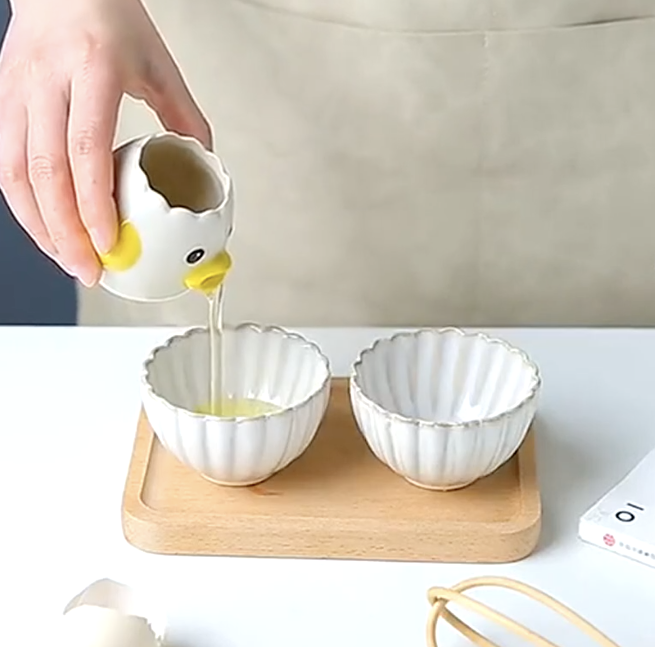 a person pouring the egg whites from the gadget into a small bowl