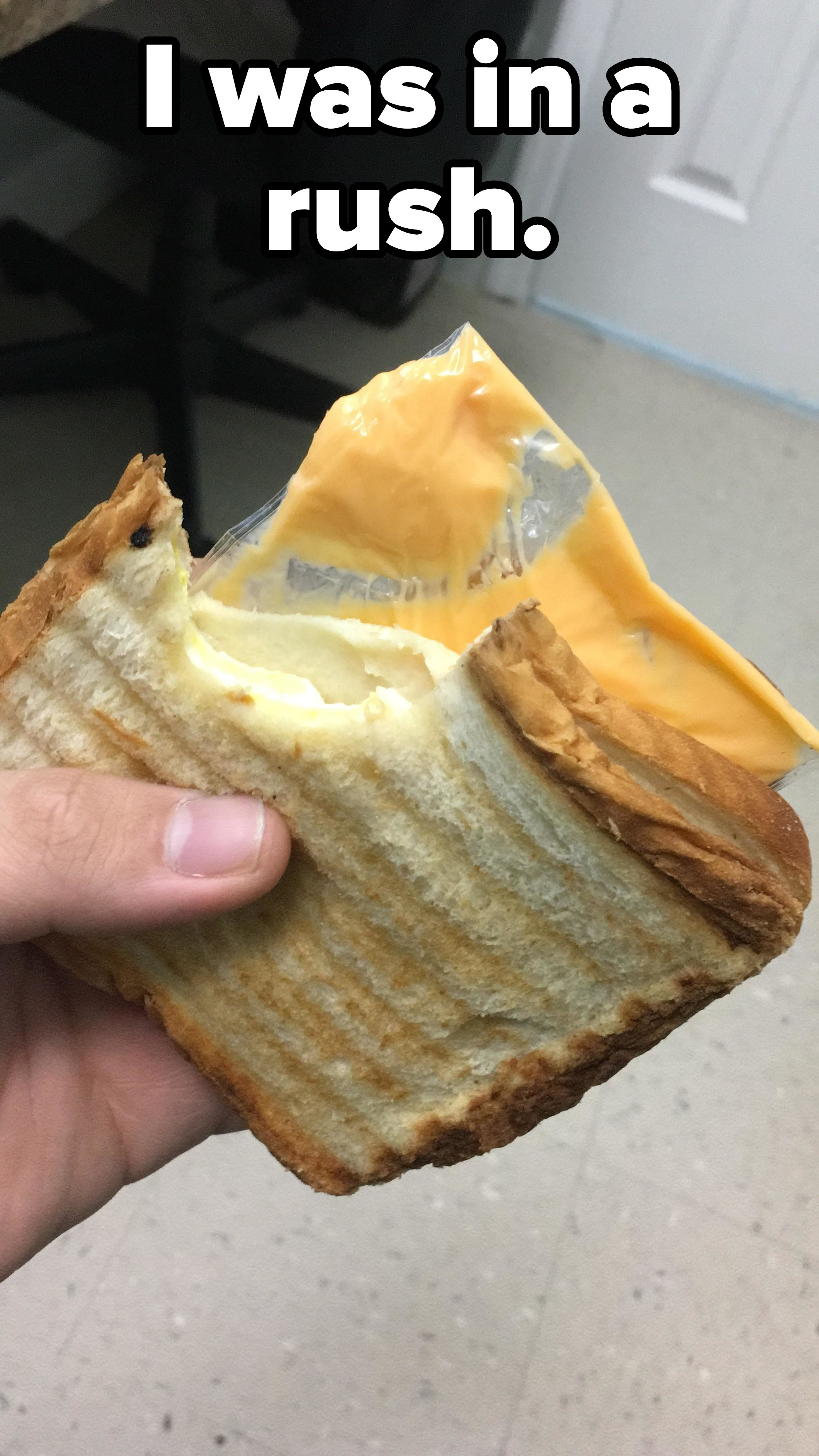 a sandwich that has a bite taken out of it with the cheese stilled wrapped up