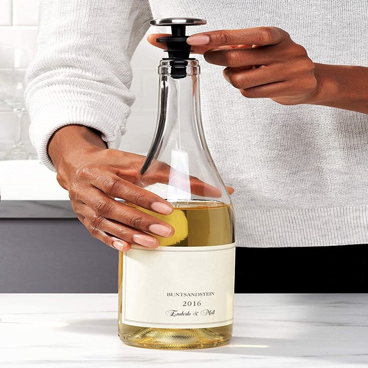 A person putting the stopper in a bottle of wine