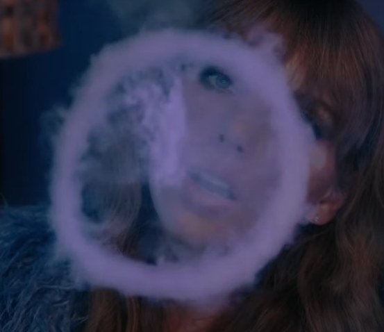 taylor blows smoke in the shape of a clock.
