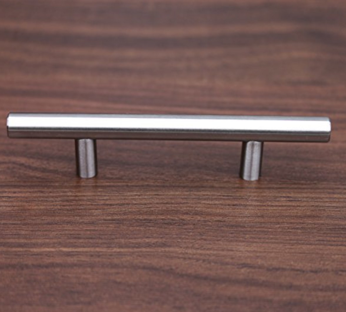 A metal cabinet handle sitting on a dark wooden surface