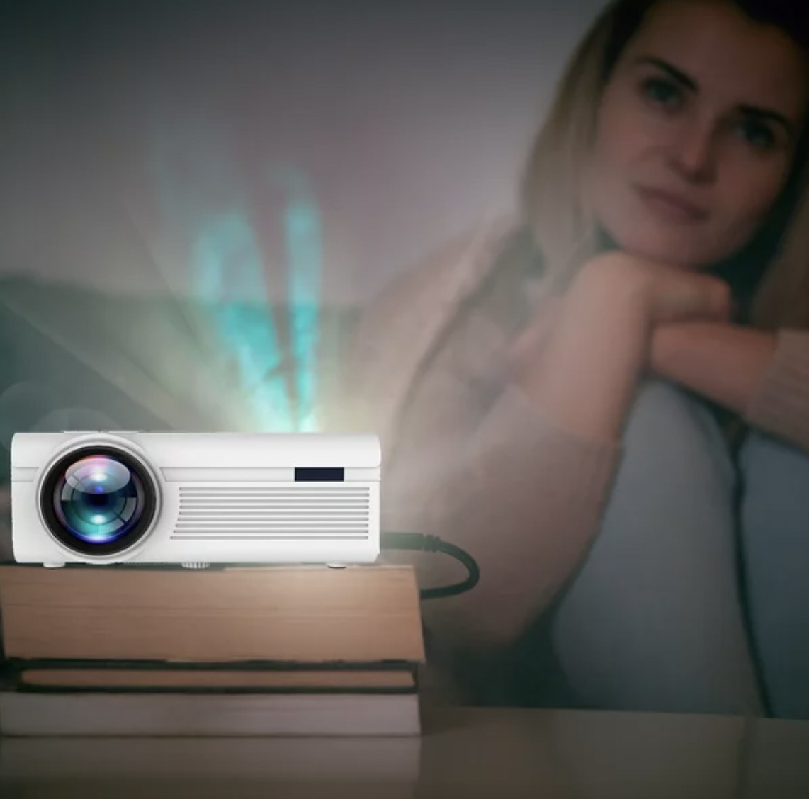 A white movie projector with a person sitting in the background