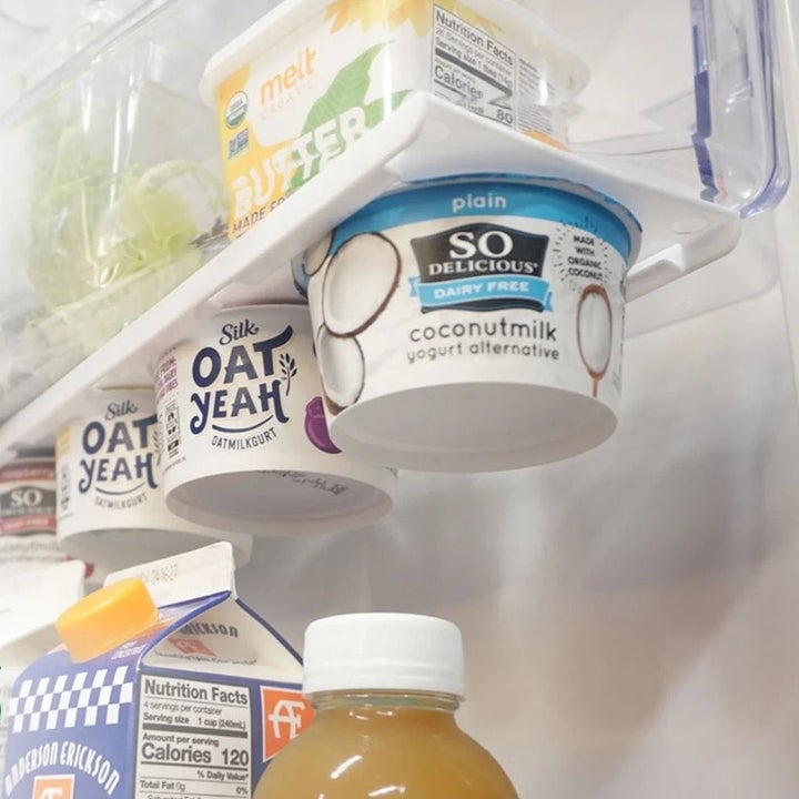 another four cups of yogurt hanging from bottom of refrigerator shelf