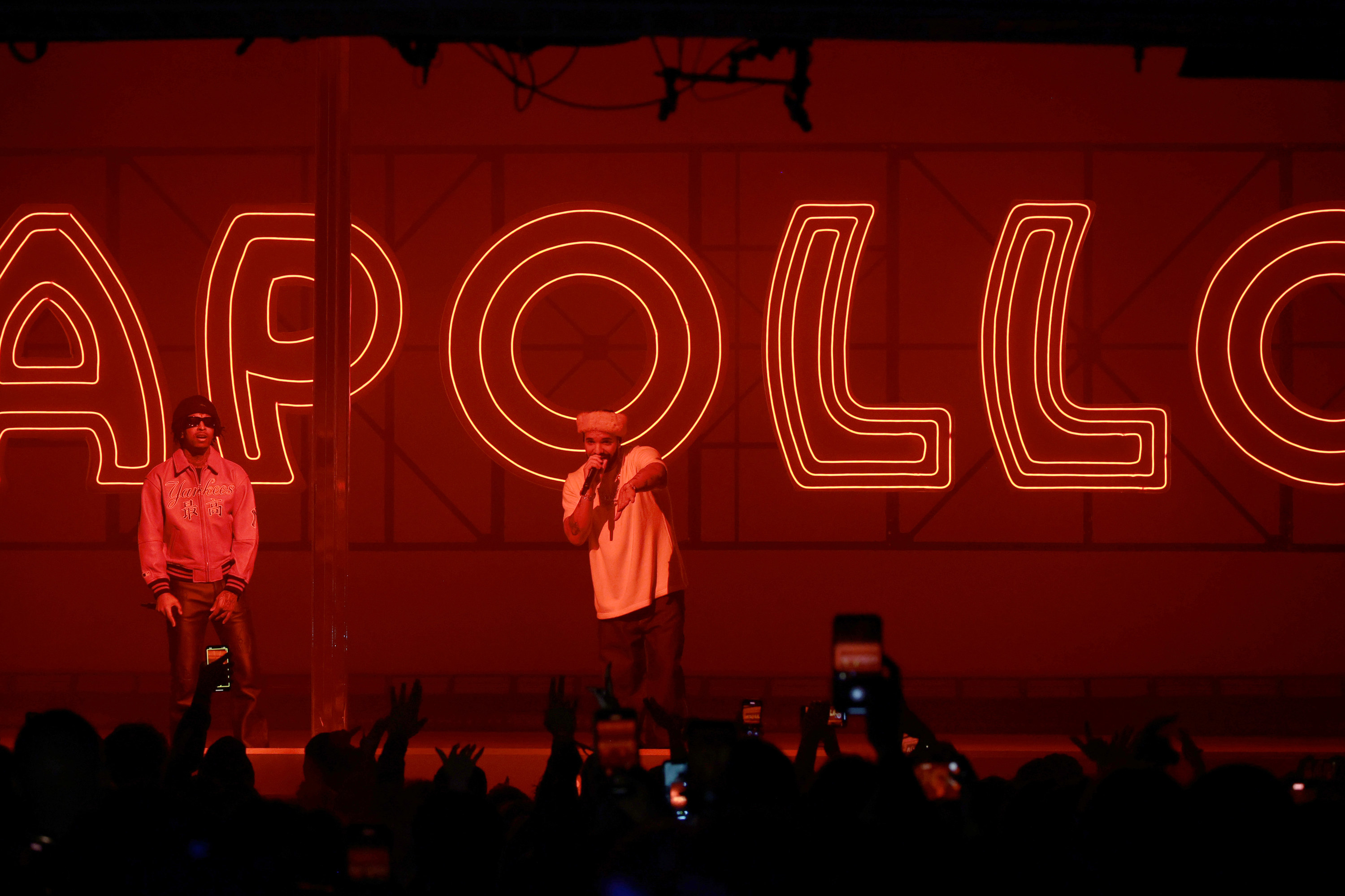 drake rapping with a neon apollo sign behind him