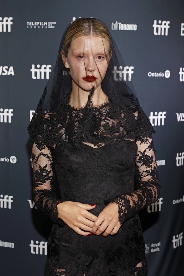 Mia on the red carpet wearing a long-sleeved lace gown with a matching veil