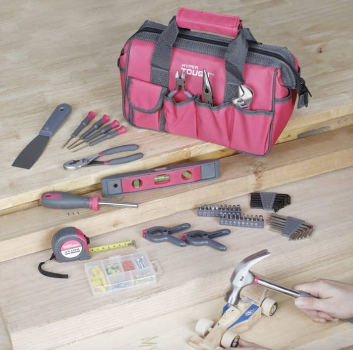 A pink tool kit with a hand hammering a wooden toy car