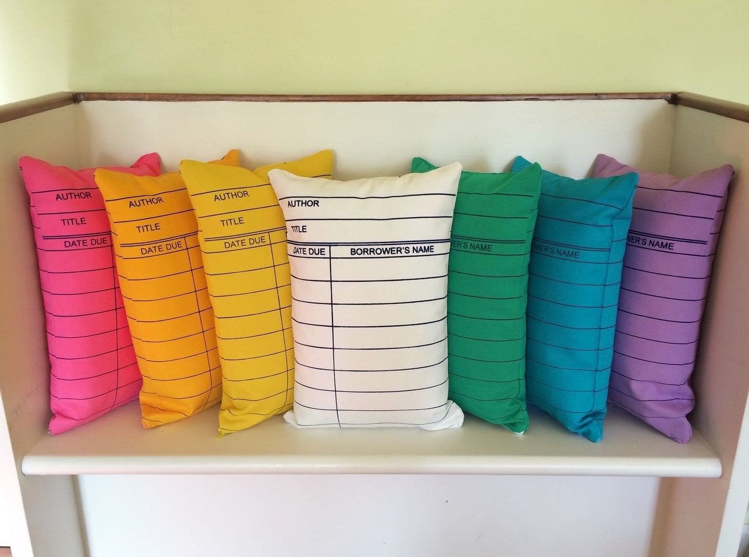 rectangular pillow printed like a library card in seven rainbow colors
