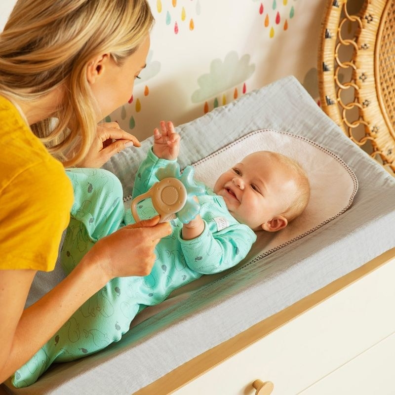 Woman plays with baby on changing mat