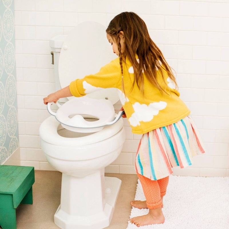 Child placing the seat cover on a toilet