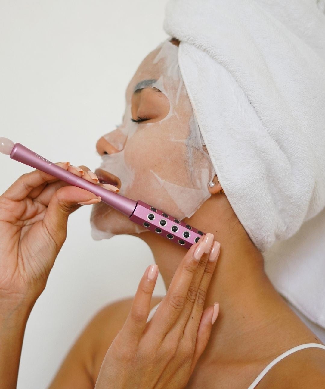 a person rolling the wand over a sheet mask on their face