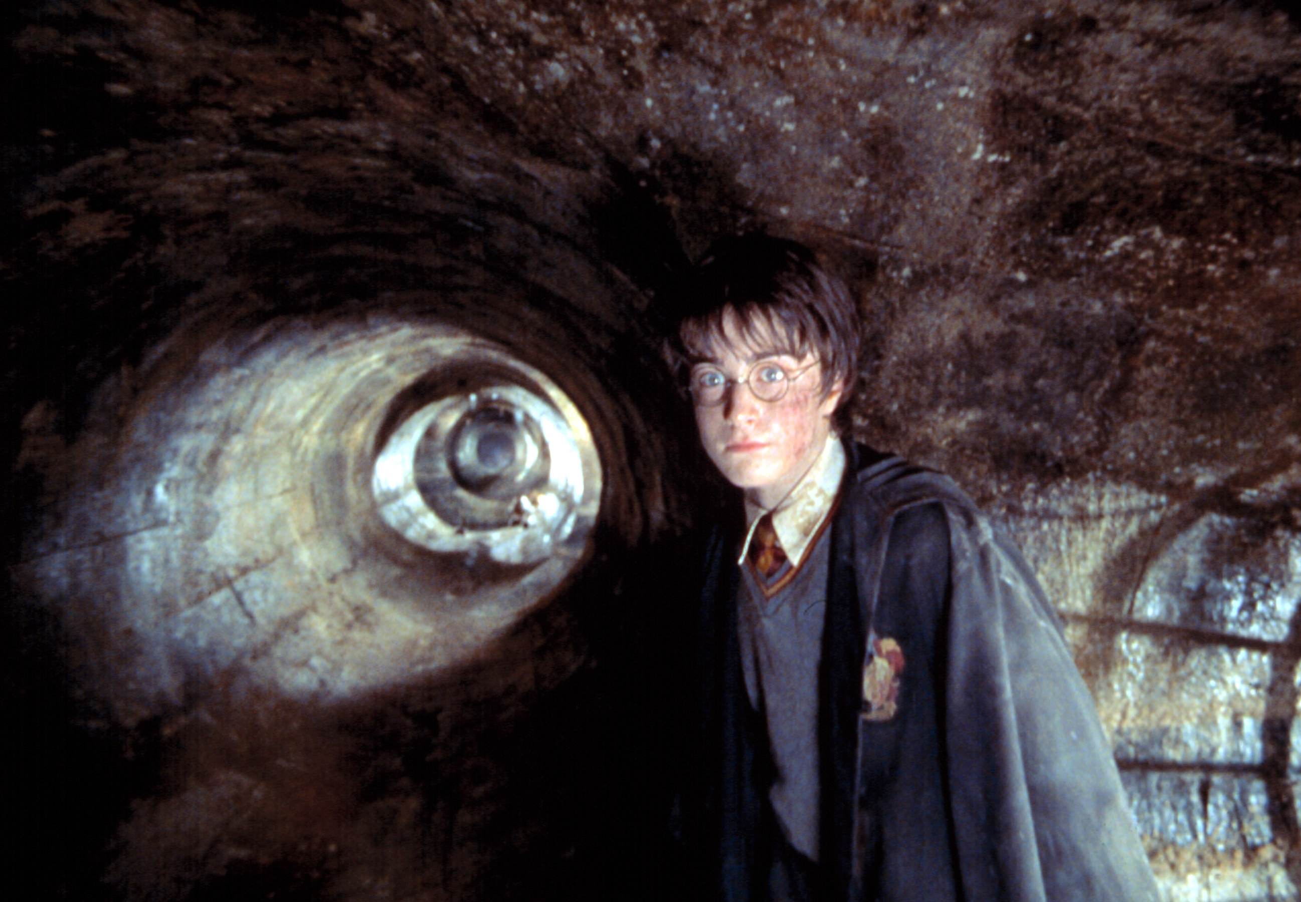 A young man stands in a sewer system, looking at something off-camera