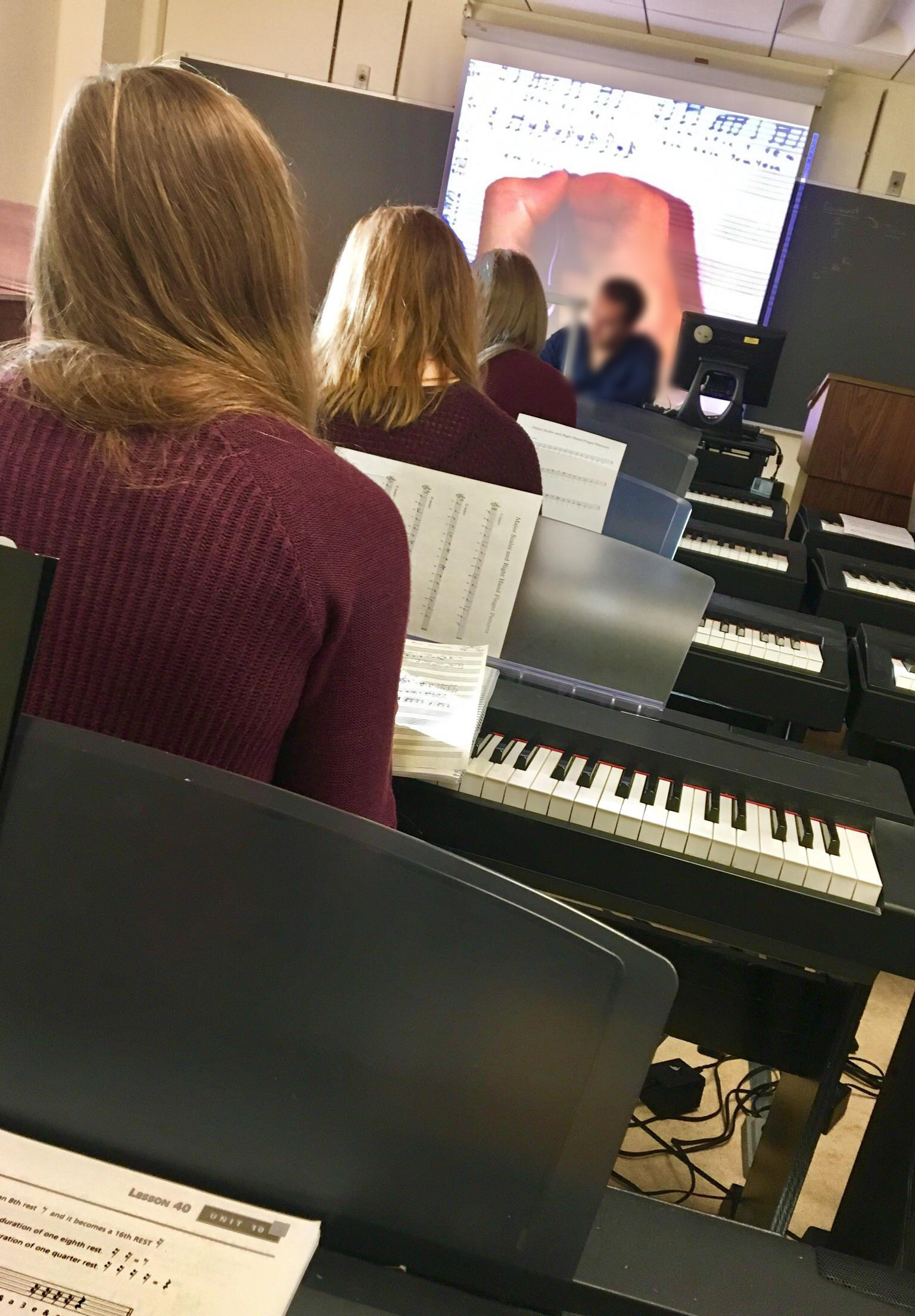 three girls sitting in a classroom teaching piano