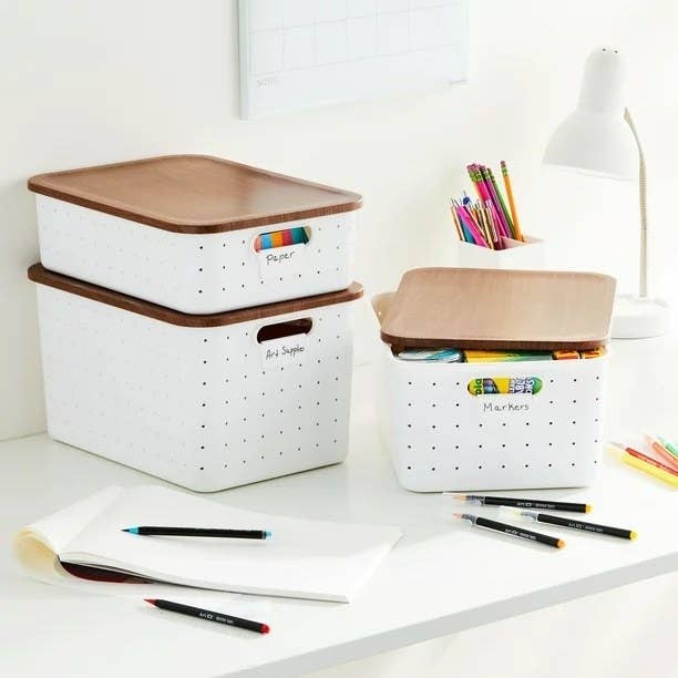 a white and faux-wood set of storage boxes holding art supplies