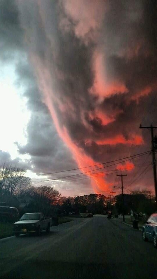A giant cloud shaped like a face with the sun setting and creating a red glow