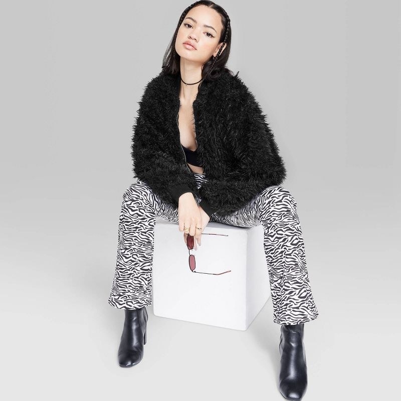 Model wearing black faux fur jacket with zebra print pants