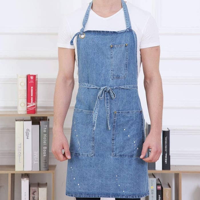 a person wearing a distressed denim apron over jeans and a t-shirt