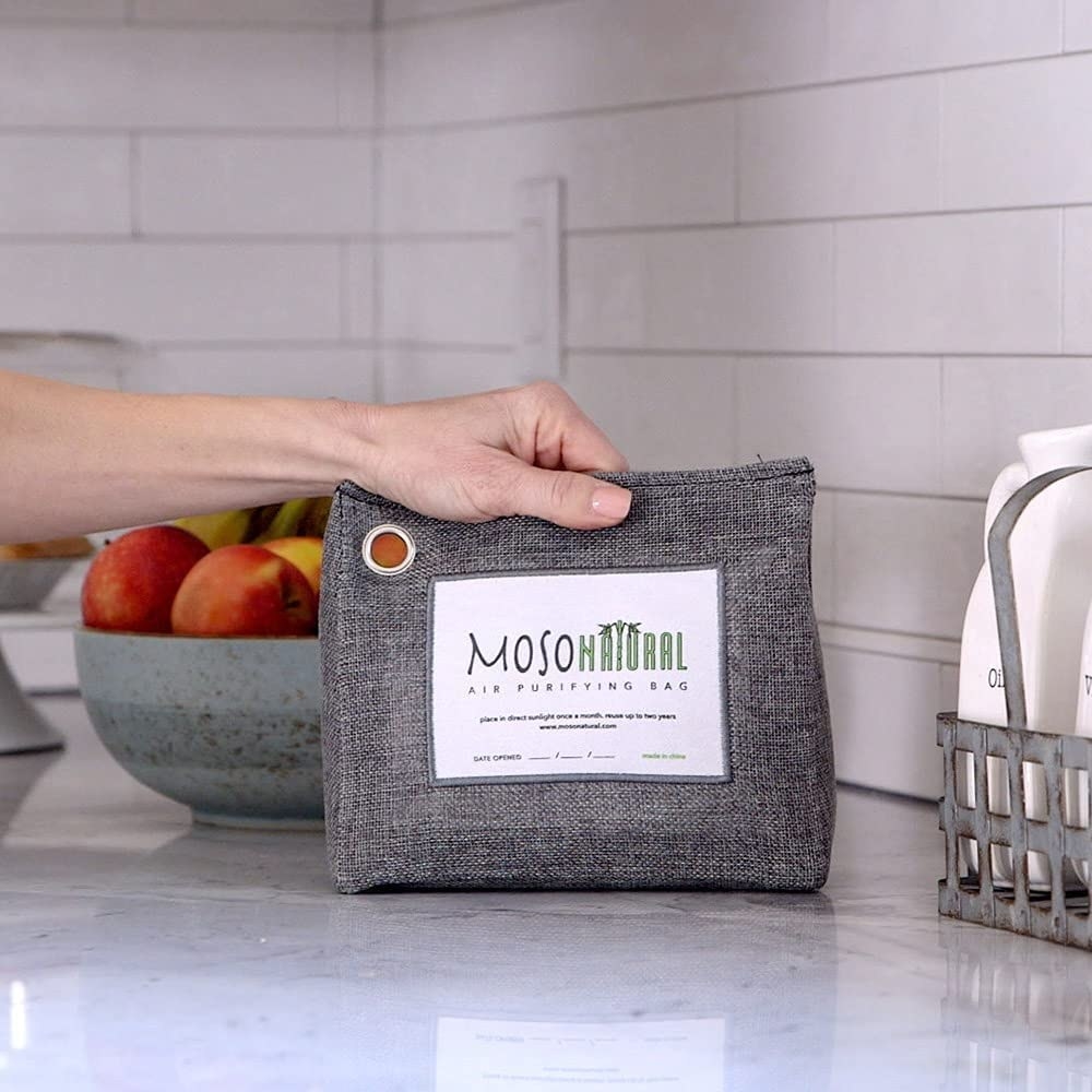a person holding a deodorizing pouch in their kitchen
