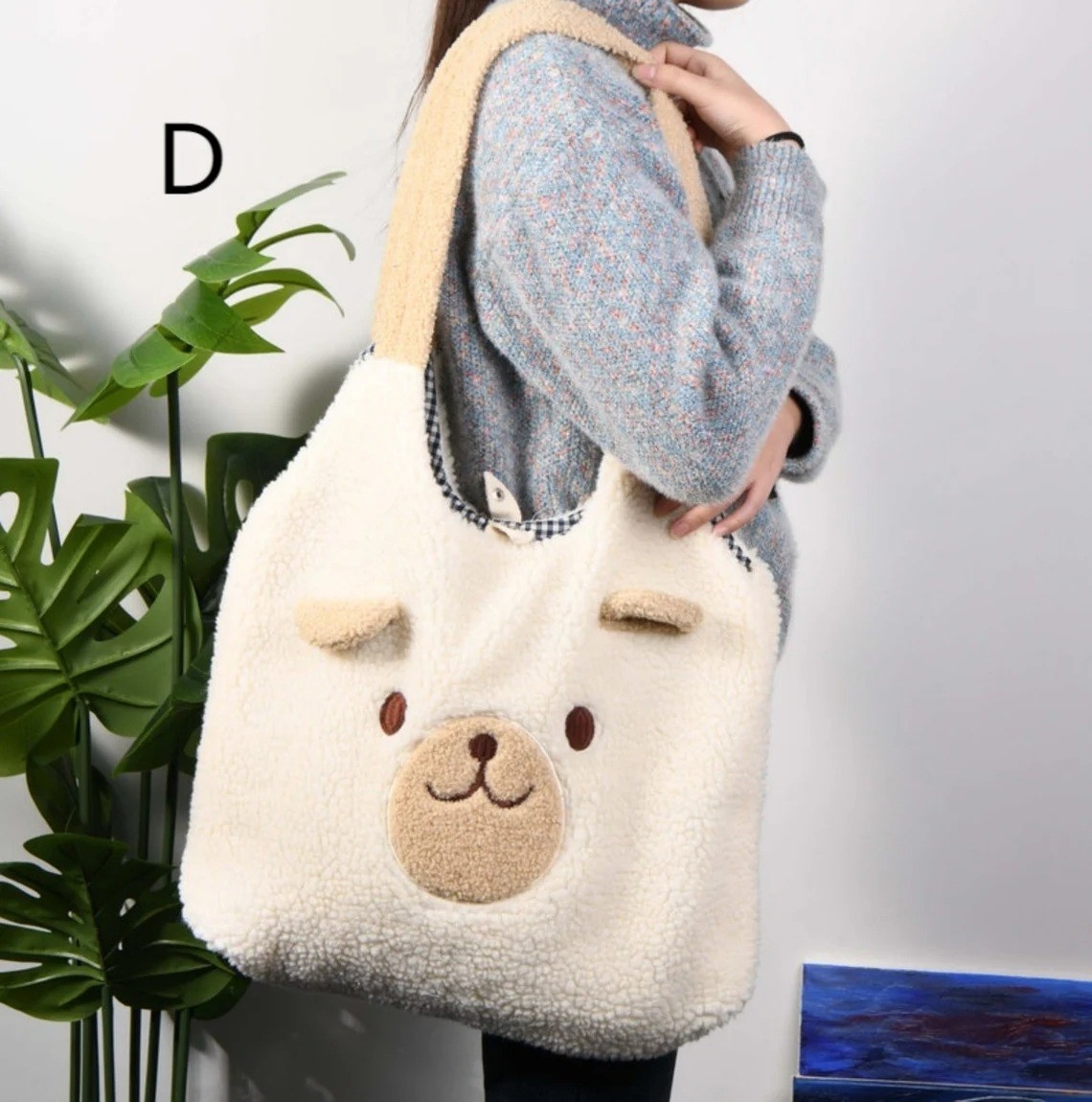model wearing a white fuzzy tote bag with a bear&#x27;s face and ears on it