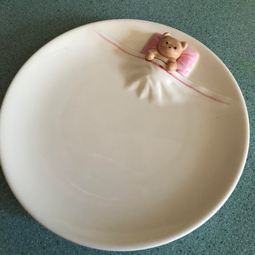 porcelain plate with a teddy bear tucked into it