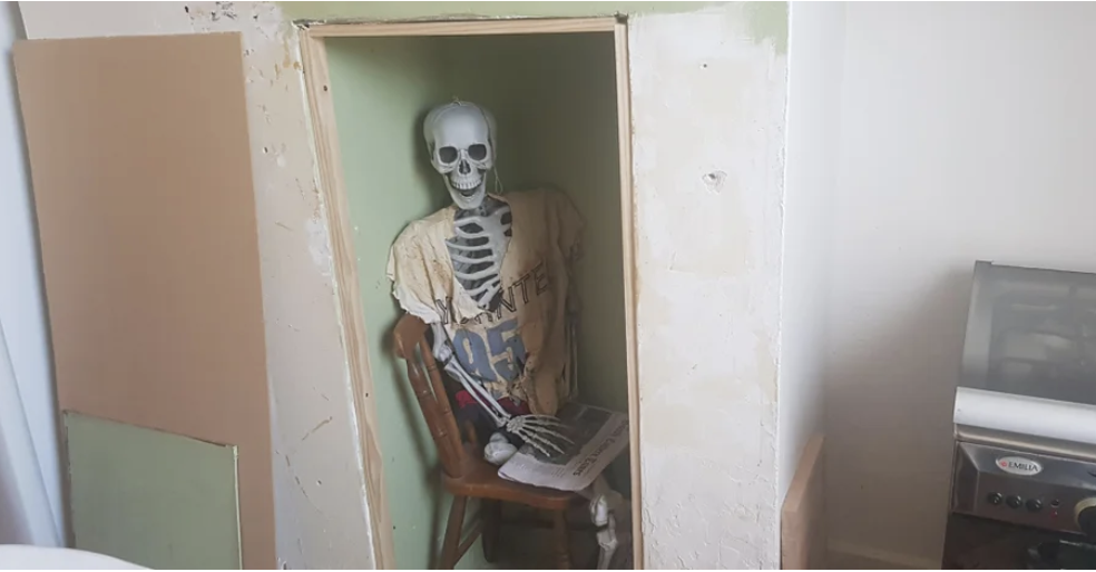 A skeleton sitting in a crawlspace