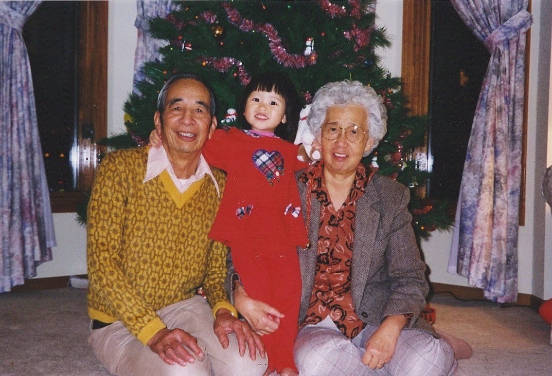 Michelle as a child with her grandparents in front of a Christmas tree