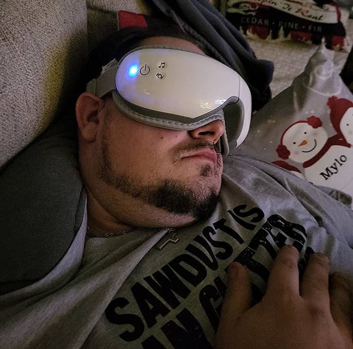 Reviewer falling asleep on couch with heated eye massager on face