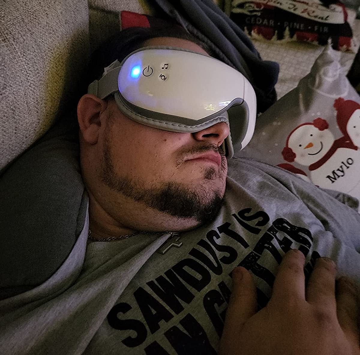 Reviewer falling asleep on couch with heated eye massager on face