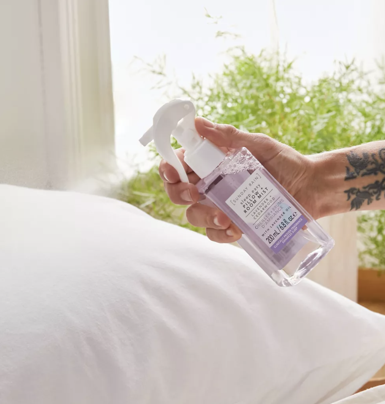 A person spritzing a pillow with the spray