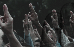 A group of people holding up the three finger salute