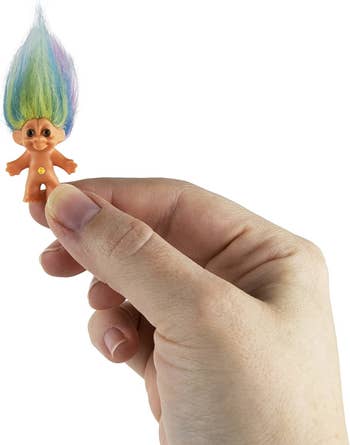 model holding a miniature troll doll with multicolor hair