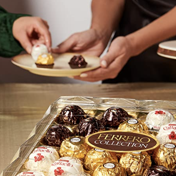 Two models passing out the chocolates with the box in the foreground