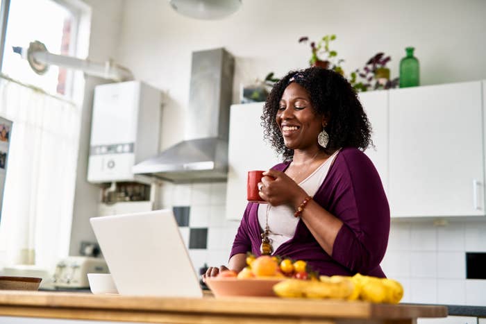 a woman sipping on a coffee talking to someone on an ipad