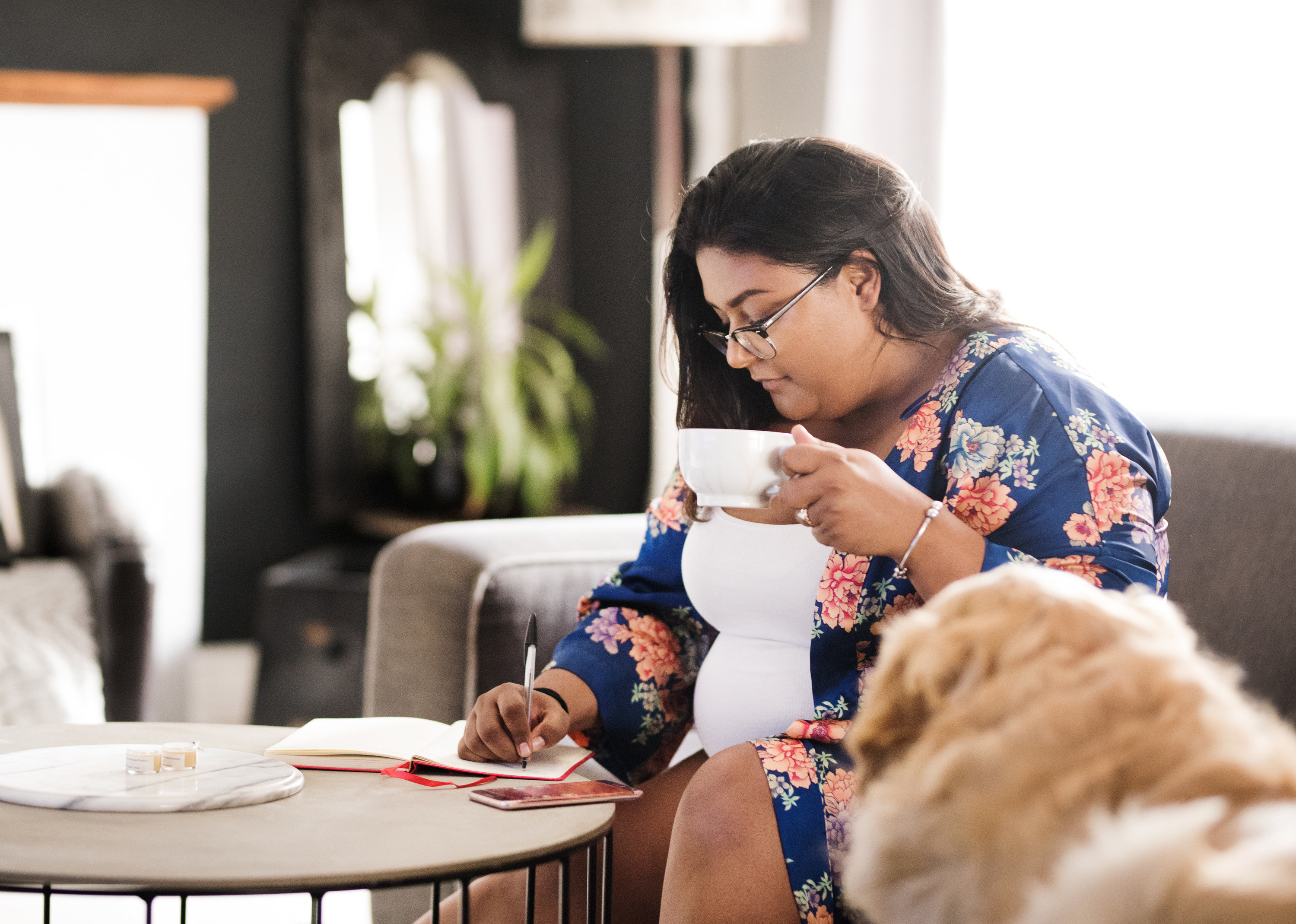 a person writing a to-do list while drinking coffee