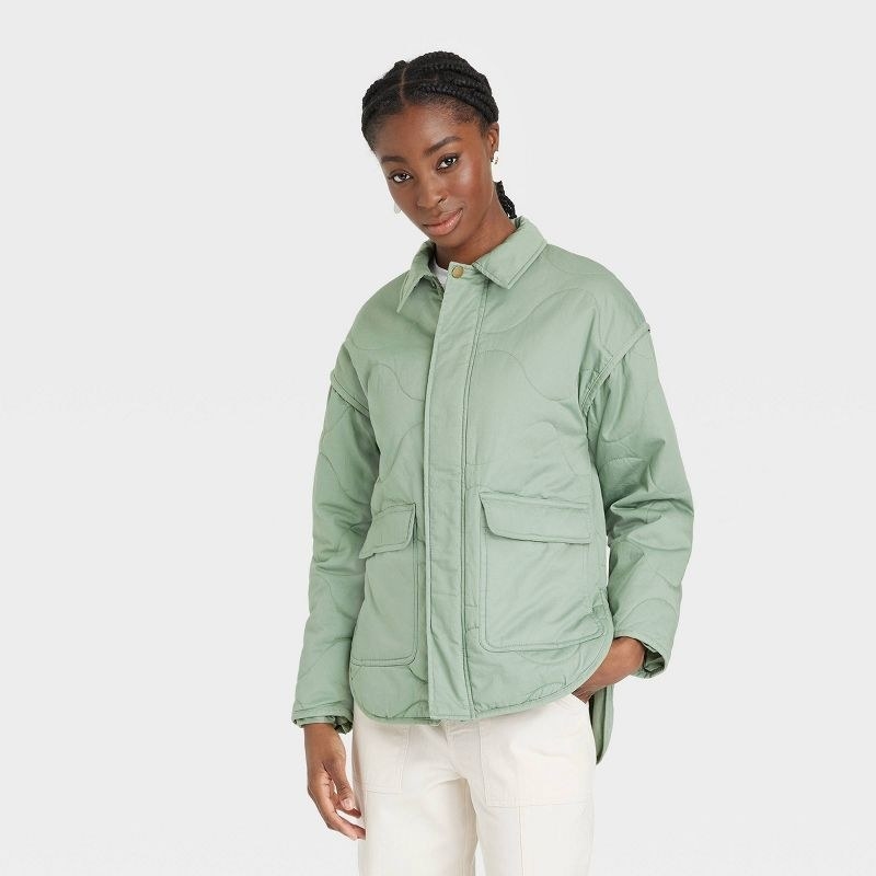 Model wearing green jacket with white pants