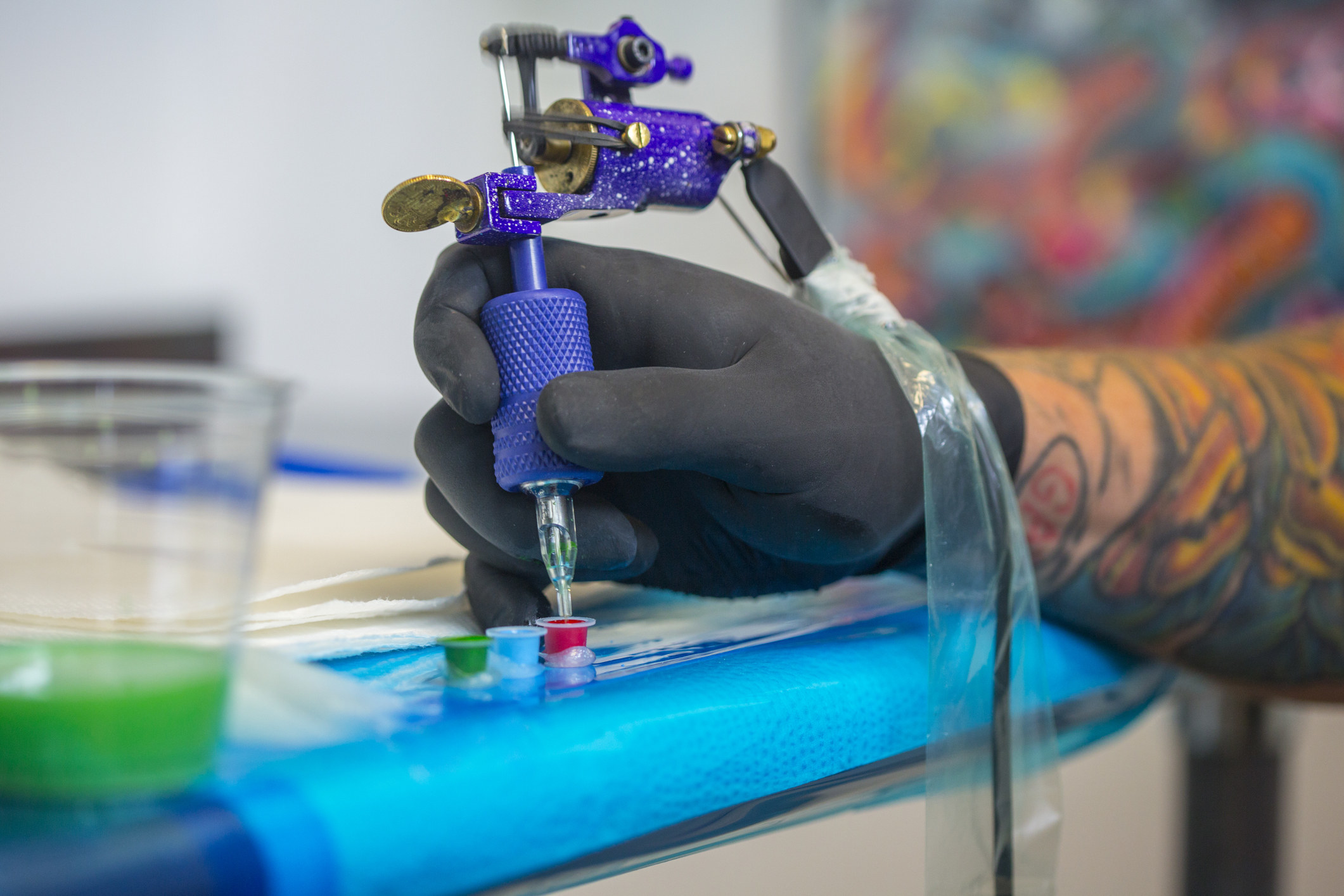 A tattoo artist dipping the gun in ink