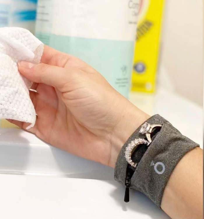 a person wearing the wristband while washing their hands; two rings are peeking out