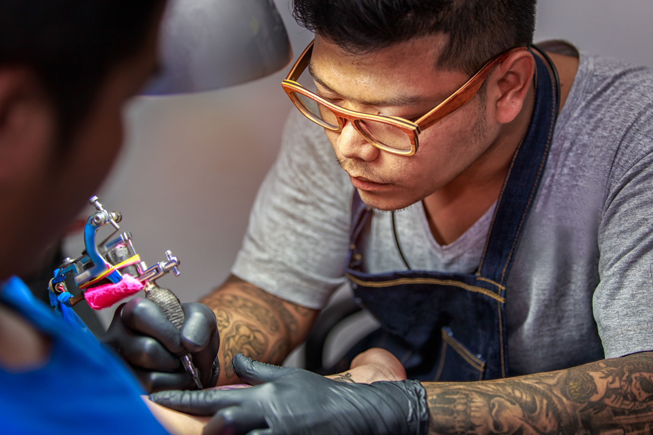 A tattoo artist working on a client