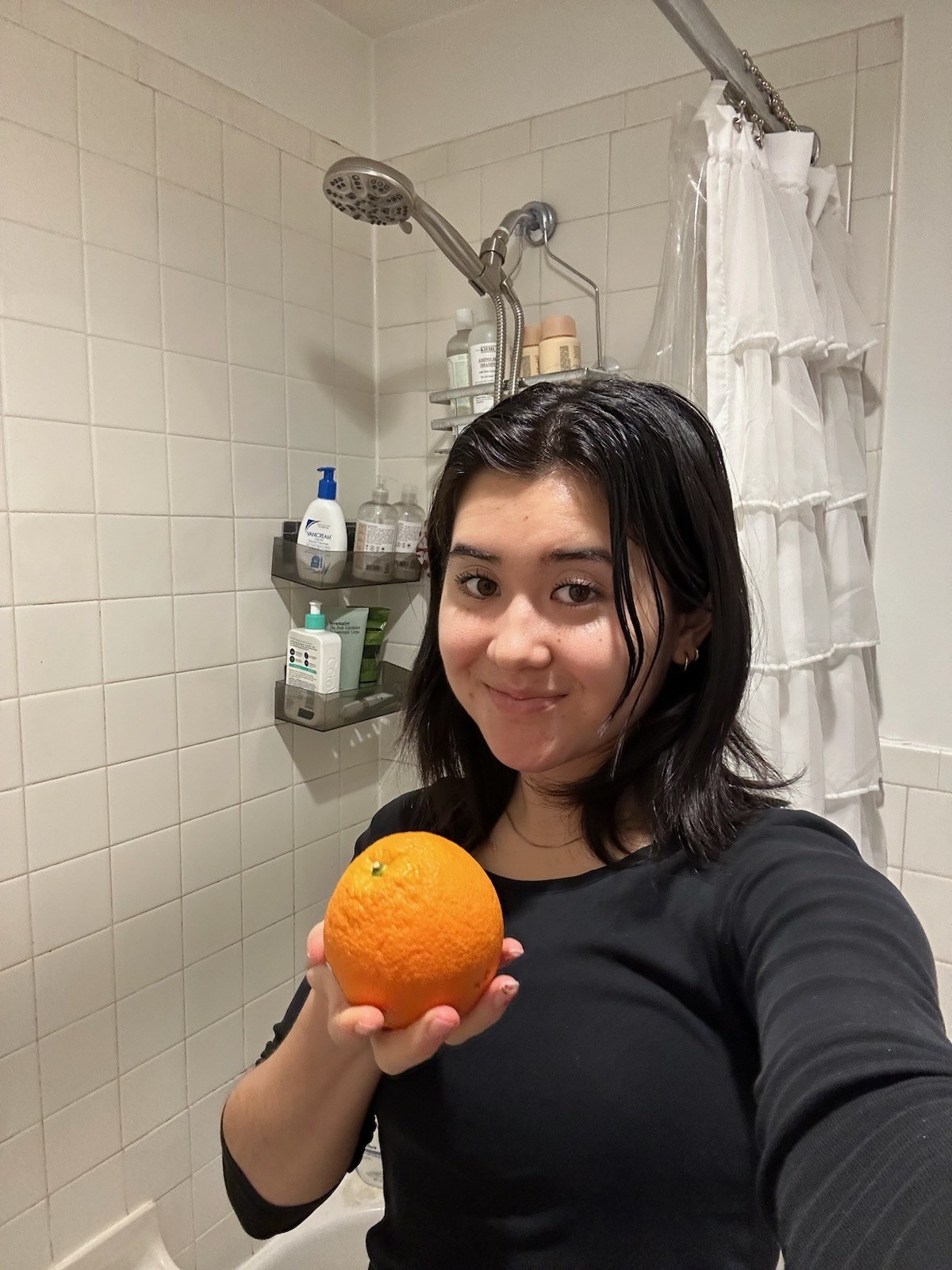 Jen standing outside the shower holding an orange