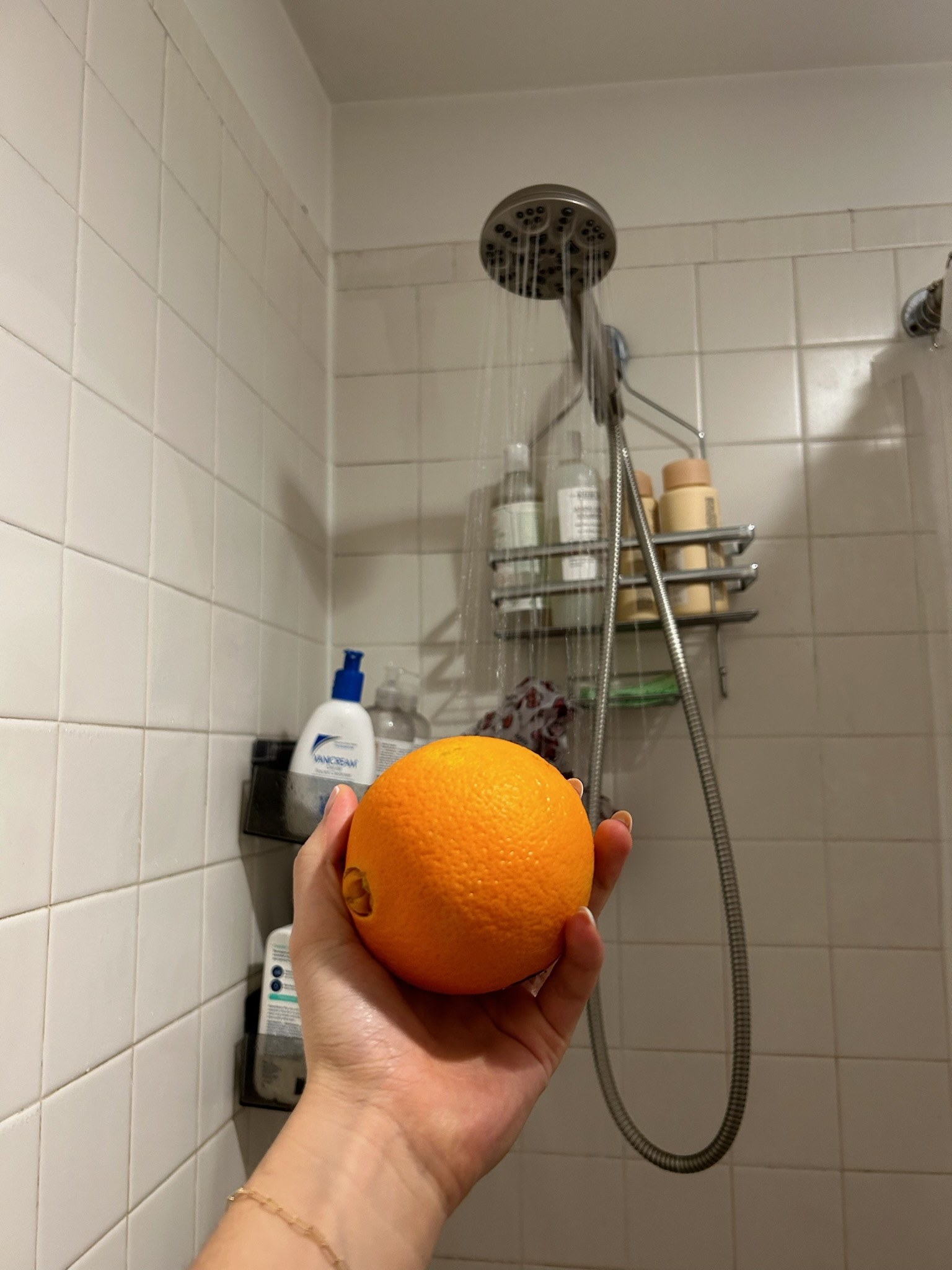 Jen&#x27;s hand holding the orange in front of the shower head