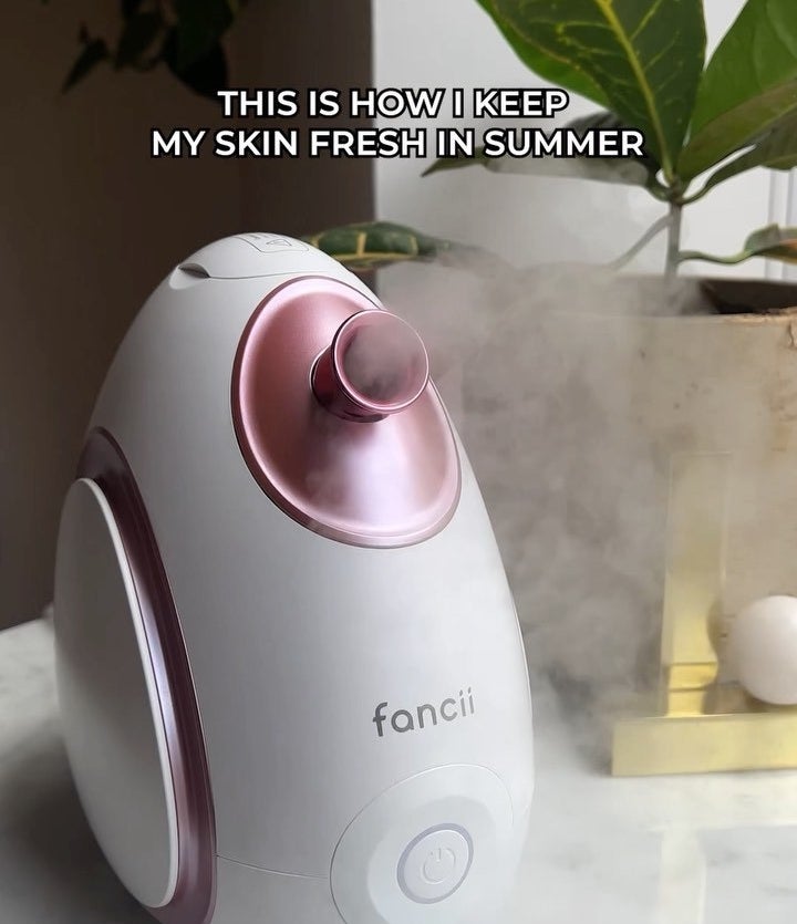 the facial steamer releasing steam from its nozzle on a countertop