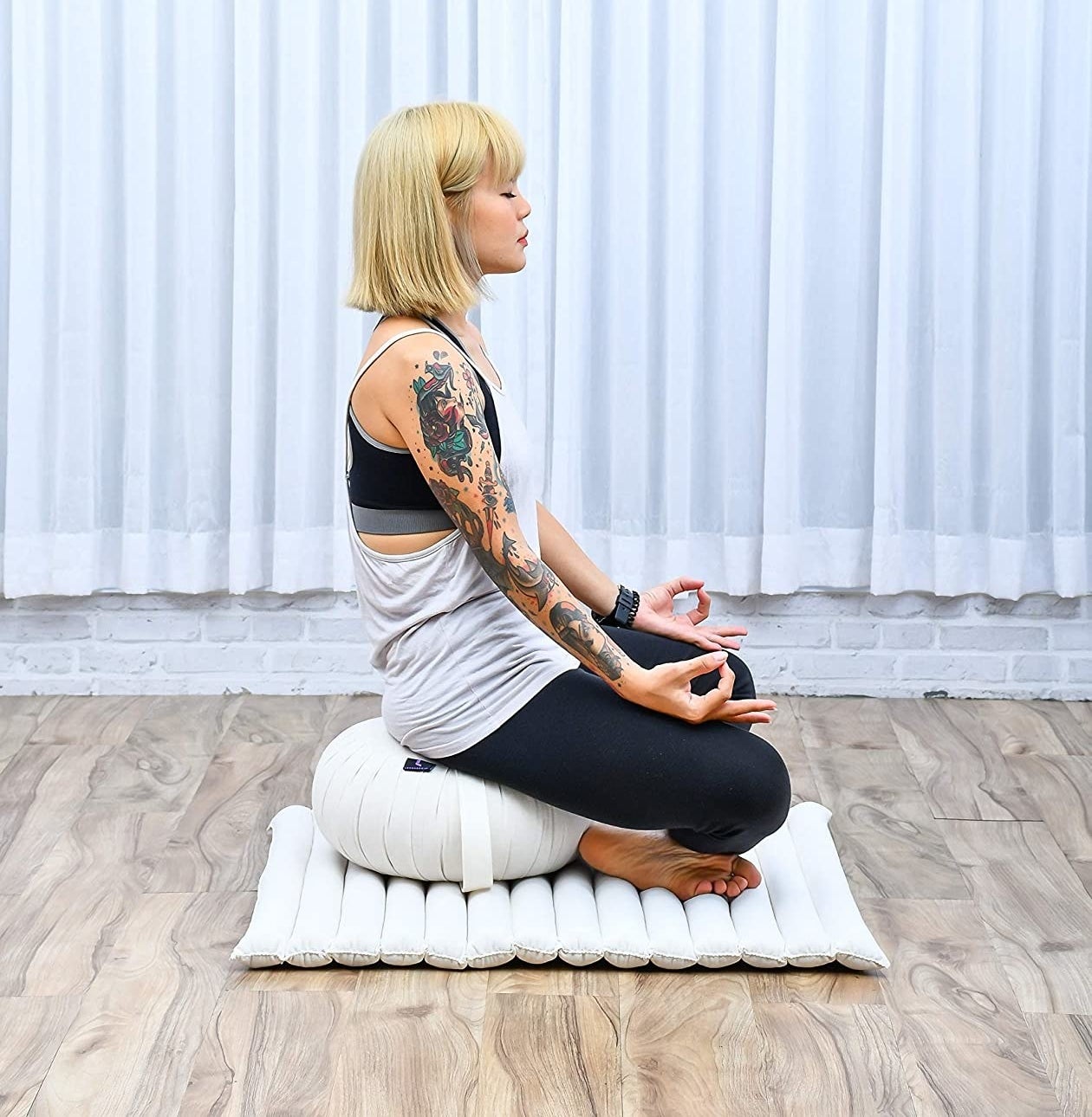 a person meditating on the stylish cushion and matching mat