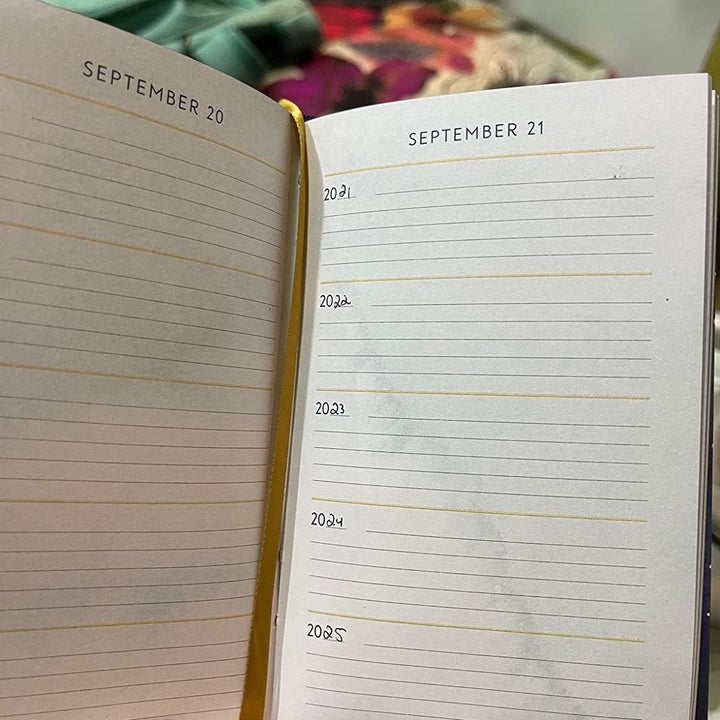 A reviewer holding open the book showing the date with five years of lines underneath