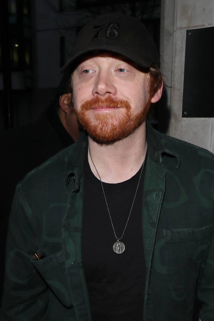 A closeup of Rupert as he walks out of a building while wearing a baseball cap