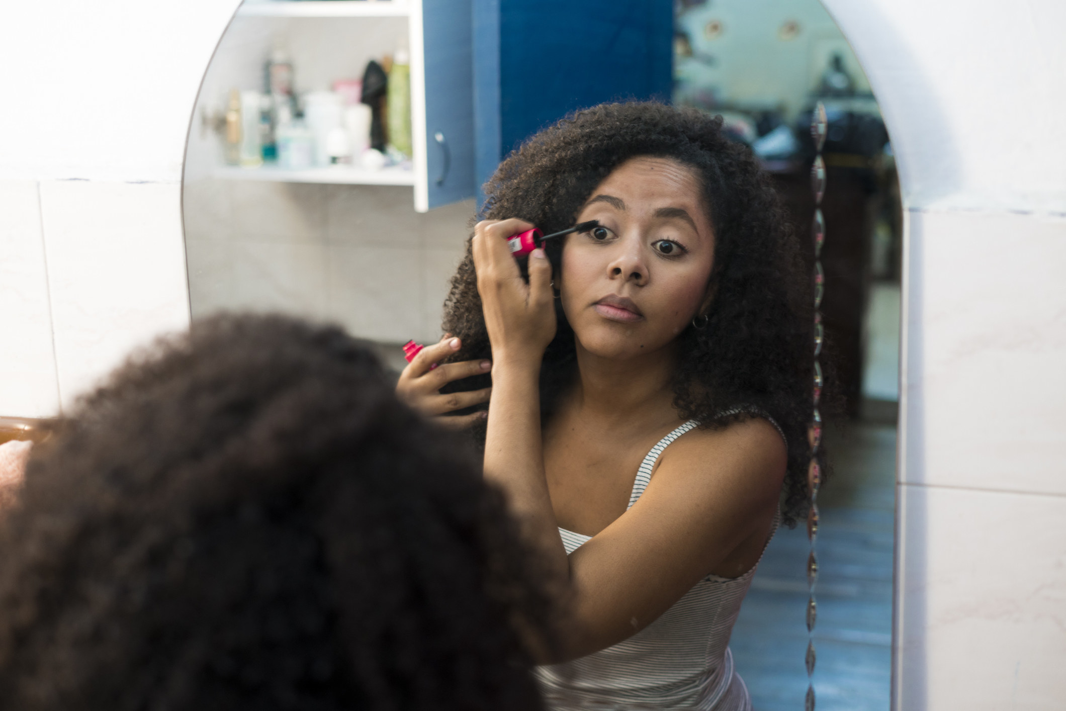 A young woman applying makeup in front of the mirror
