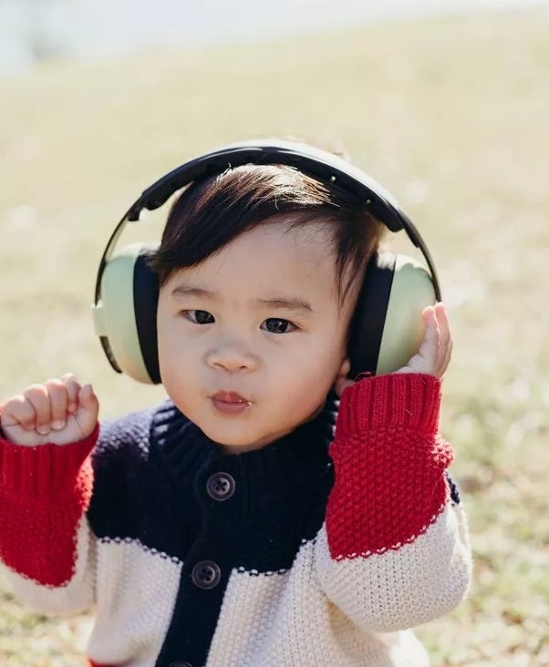 Baby model wearing green and black headphones on head